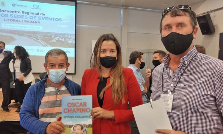 Fernanda Rodríguez, directora nacional de Fiestas Populares, recibiendo el libro que recuerda a Oscar Chapino, de parte de Alejandro Comas y Darío Weglin.
